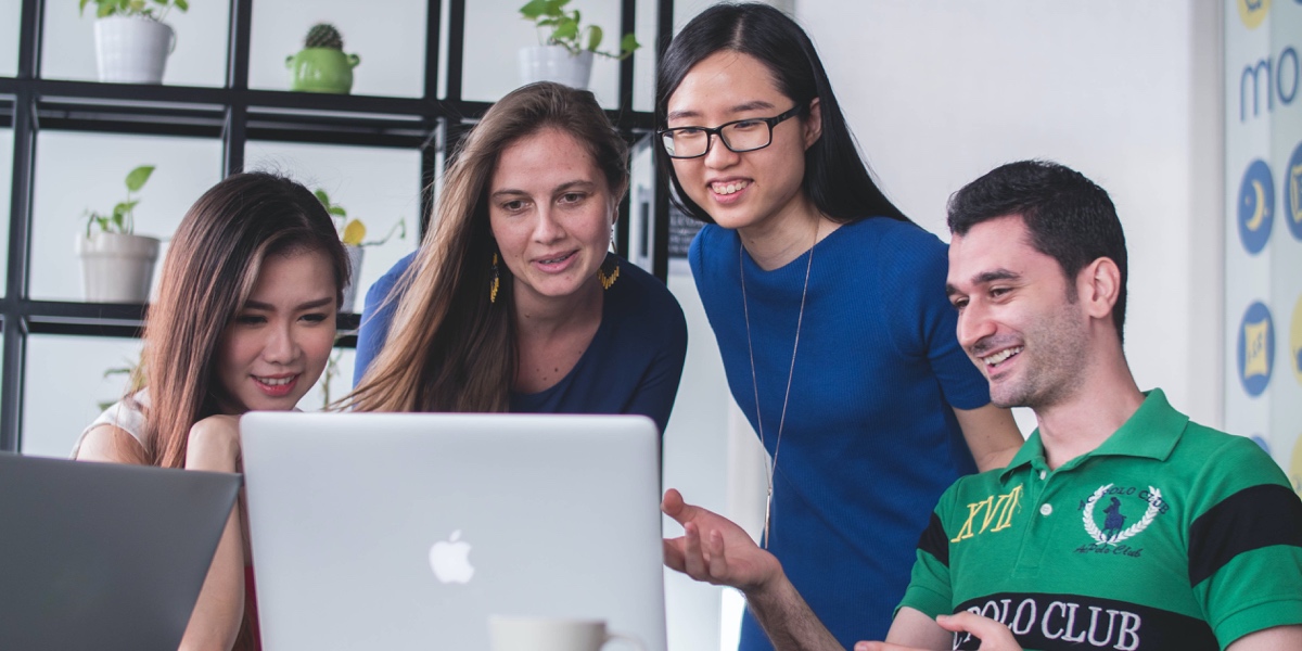 Four UX writers gathered around several laptops, collaborating on a project