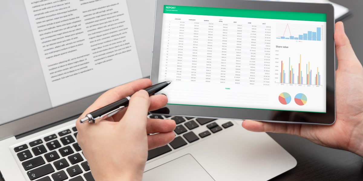 A laptop with text data on the screen, and a tablet displaying data and graphs A laptop with text data on the screen, and a tablet displaying data and graphs