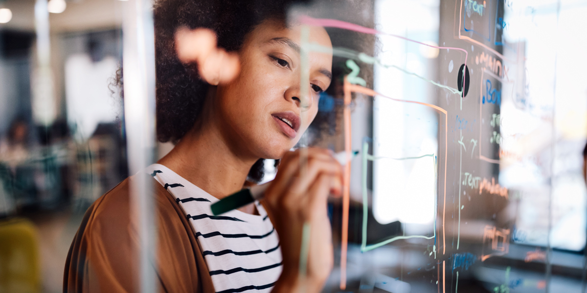 UX designer mapping out their thoughts on a glass wall