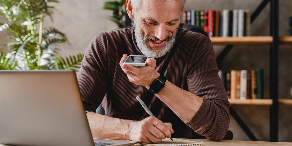 Am I Too Old for a Career in UX? UX designer working at their desk, speaking into a phone and taking notes