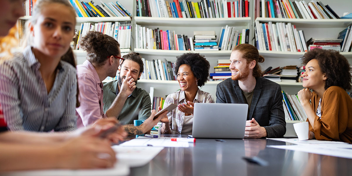 A group of designers sitting around a table having a brainstorming session A group of designers sitting around a table ideating