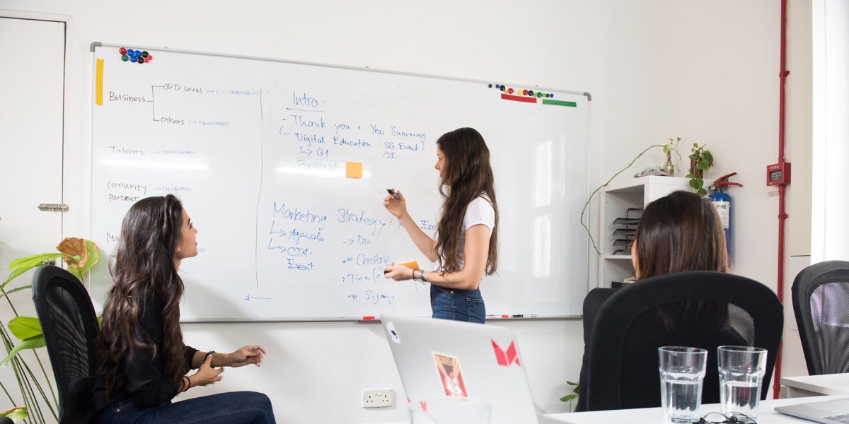 Three designers in an office, ideating at a whiteboard