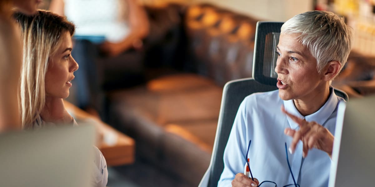 Benefits of Having a UX Design Mentor An aspiring UX designer sitting at a desk with her mentor