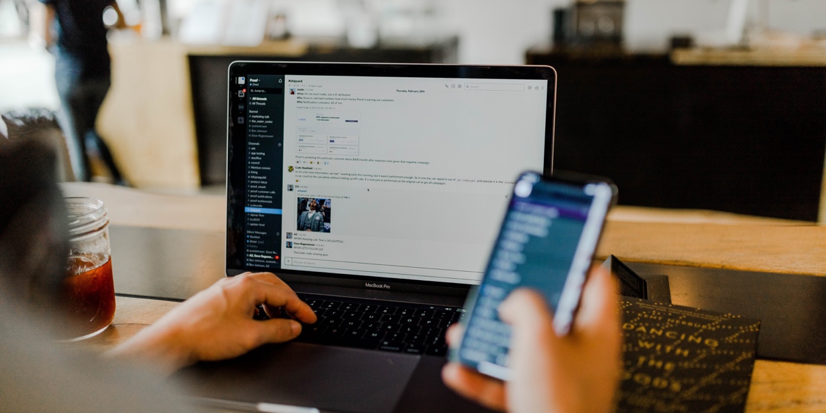 A UX writer using Slack on their laptop and to collaborate with their team