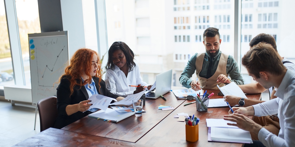 A small group of professionals conduct a SWOT analysis in an office environment
