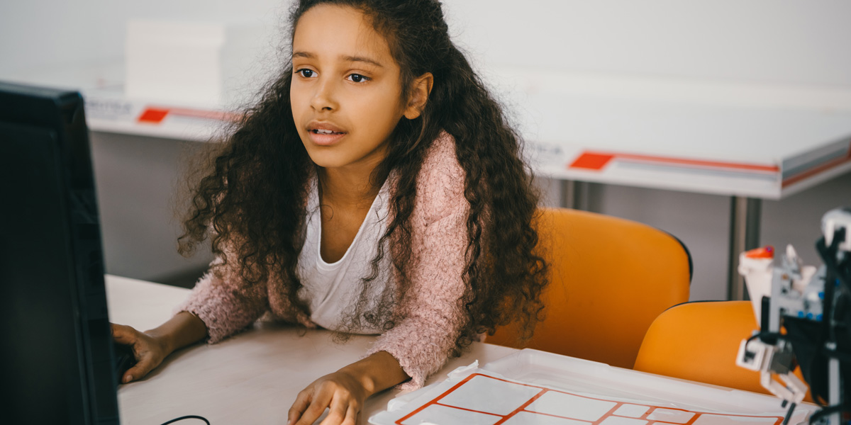 A young girl sitting at a desk, working on a computer