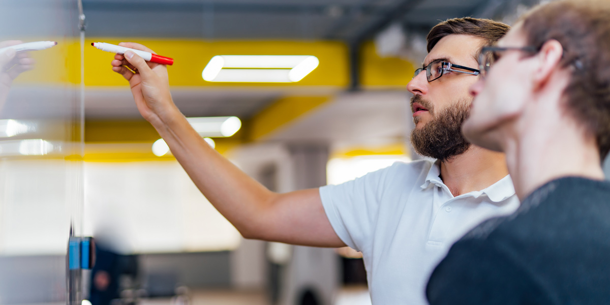 Two designers standing at a whiteboard, discussing their empathy map