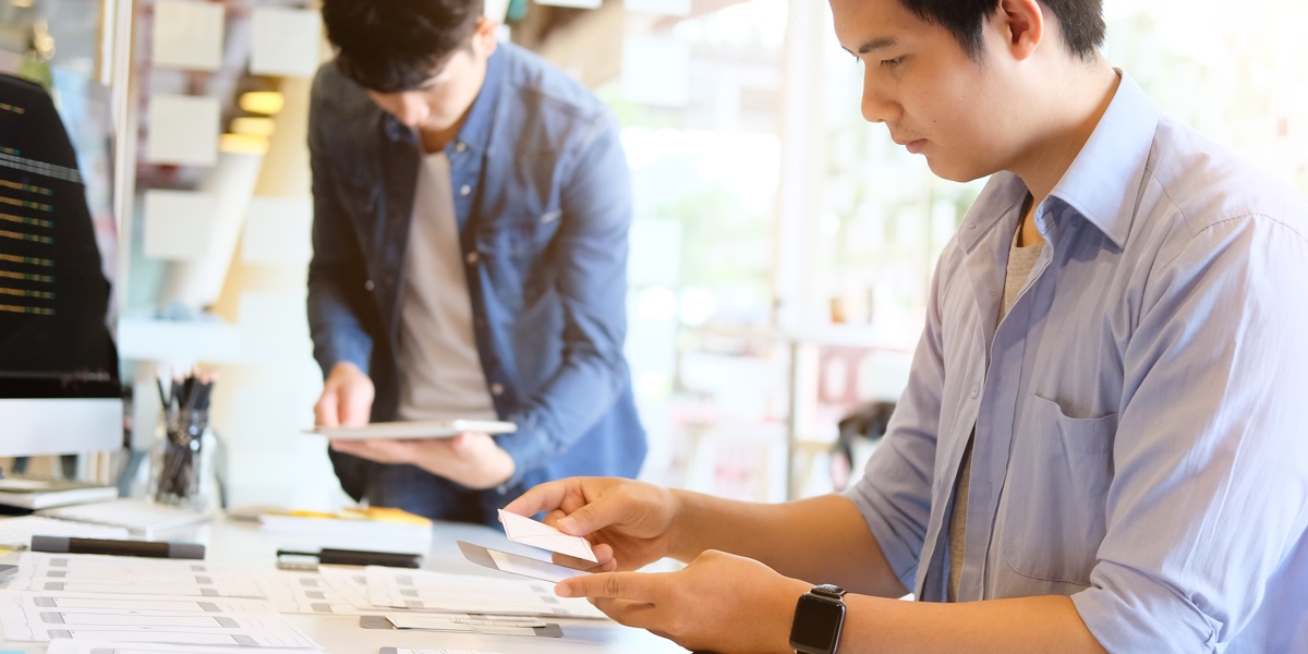 Two designers working at a desk, reviewing their process and getting ready to iterate