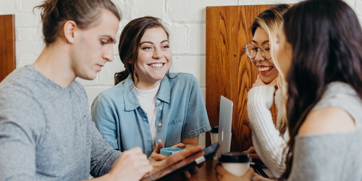 What's It Like to Be a UX Designer? Four tech professionals sitting at a coffee shop, collaborating on a design project