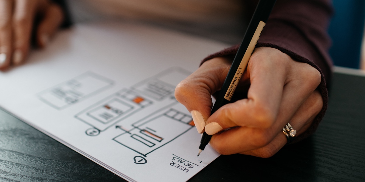 Close-up of a UX designer's hand, working on a paper prototype
