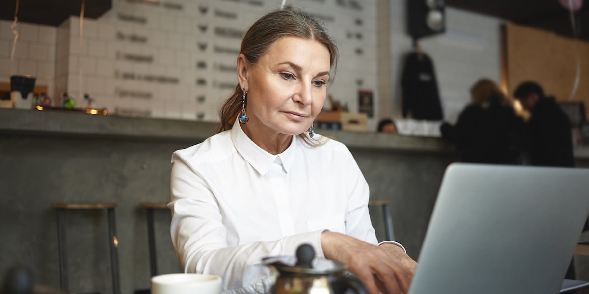 A UX designer sitting in a cafe with her laptop, considering psychology and UX design