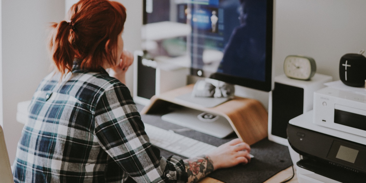 The Power of Storytelling in UX Designer facing away from camera, working on a desktop computer.