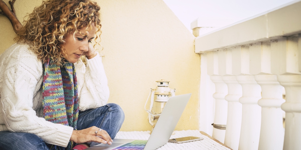 An aspiring UX writer, sitting comfortably on a porch with a laptop