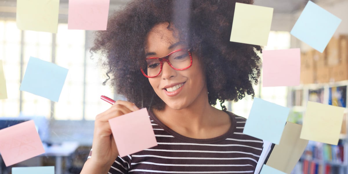 A web designer working on a glass wall with post-it notes