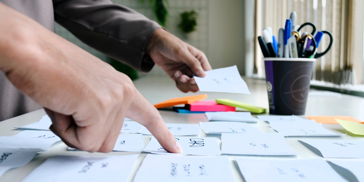 A desk area covered in sticky-notes and two designers sorting through the ideas