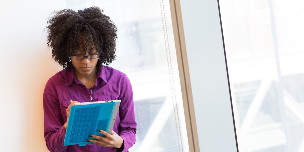 UX designer, standing near a large window, writing ideas in a notebook