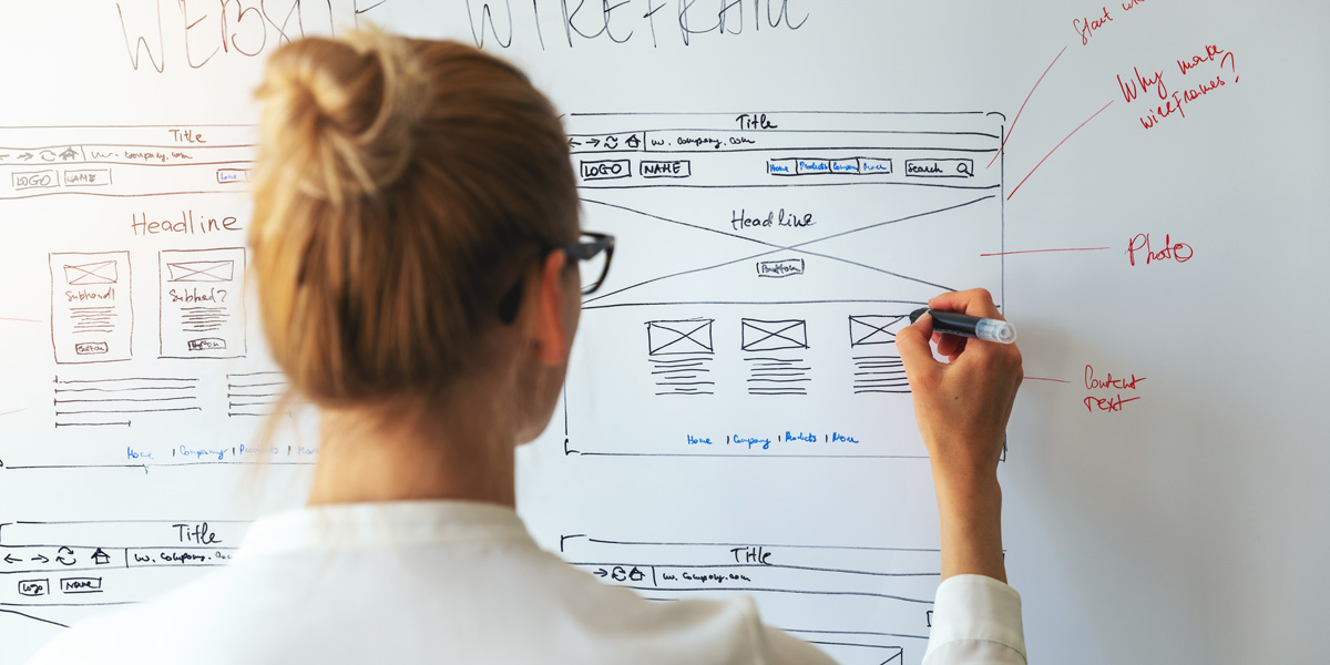 How To Learn UX Design And Become A UX Designer A person trying to learn UX design, standing at a whiteboard, drawing wireframes